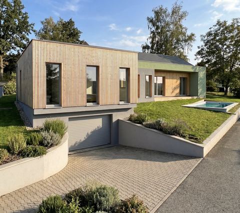 Image de projet : maison en bardage bois vertical et enduit vert, garage en soubassement et petite piscine dans le jardin